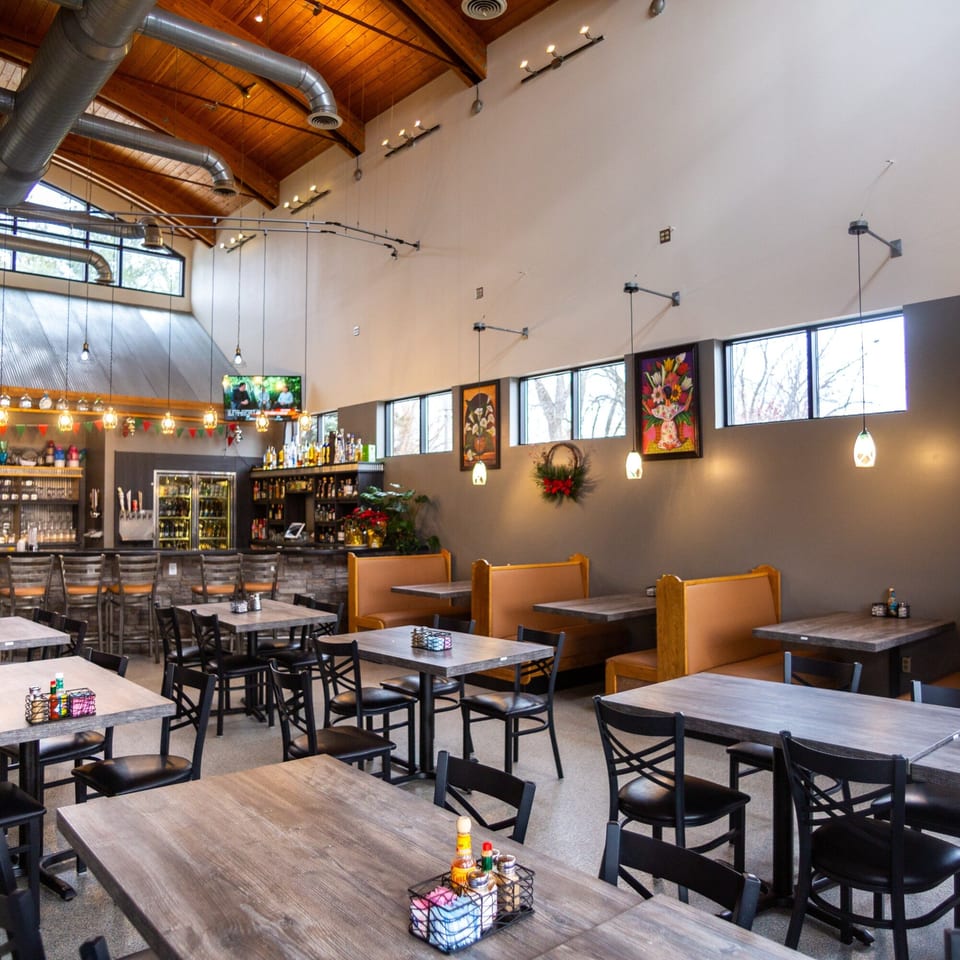 Spacious dining area at Casa Agave Mexican Cuisine with tables, booths, a bar, and high ceilings.
