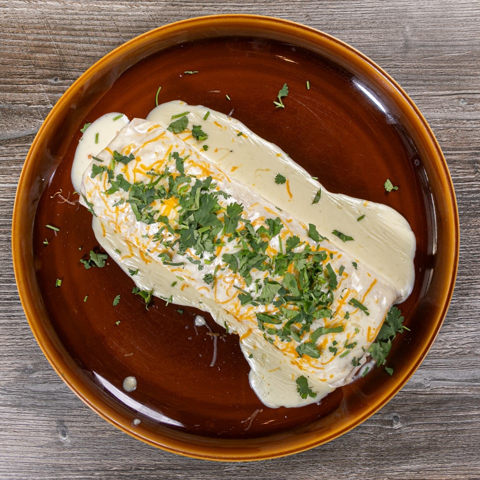 Casa Agave's Mexican burrito, smothered in white sauce, topped with shredded cheese and fresh cilantro.