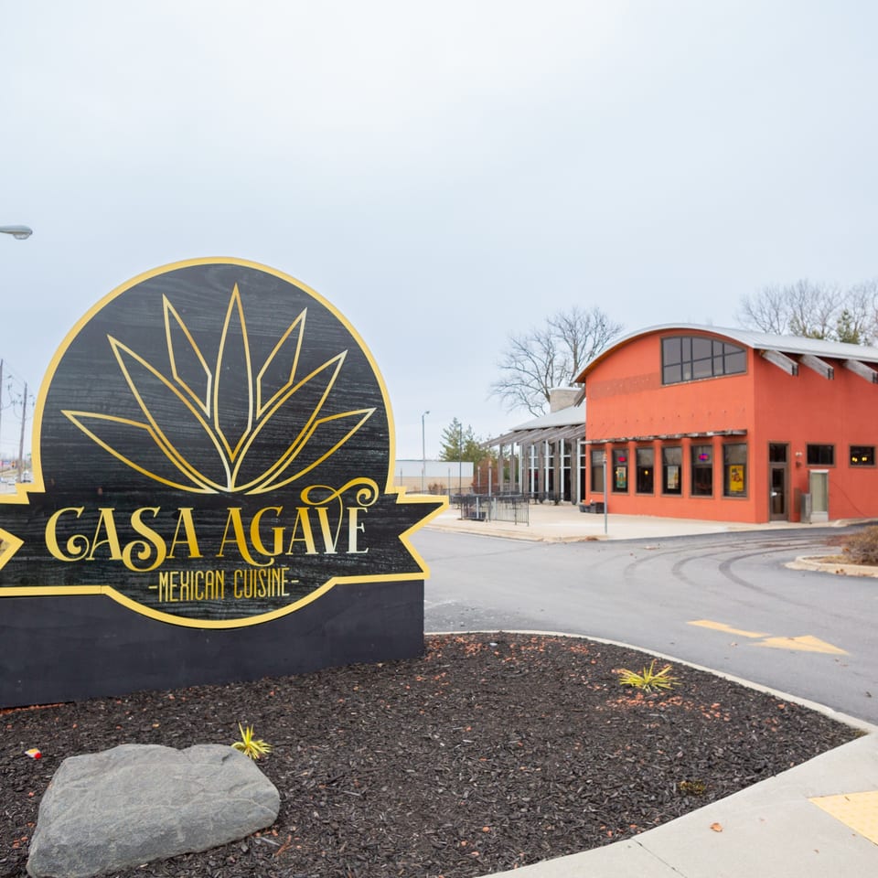Casa Agave Mexican Cuisine sign in front of the orange restaurant building and parking lot.