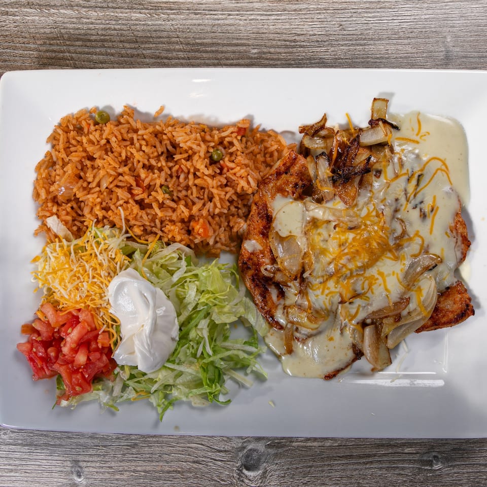 Casa Agave's Mexican dish with rice, grilled chicken, onions, cheese sauce, lettuce, tomatoes, and sour cream.